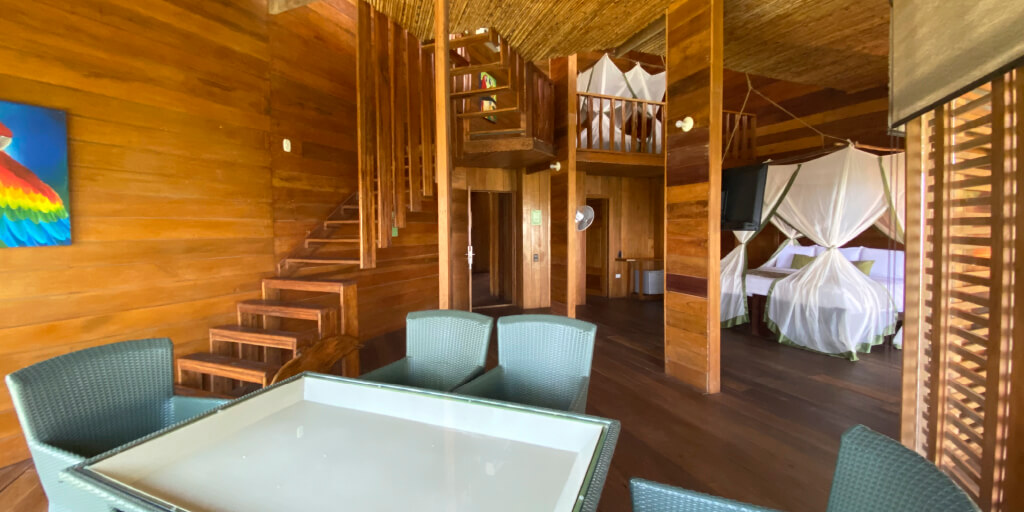 Suite de dos niveles en madera, con sala, escalera al altillo y cama con toldillo